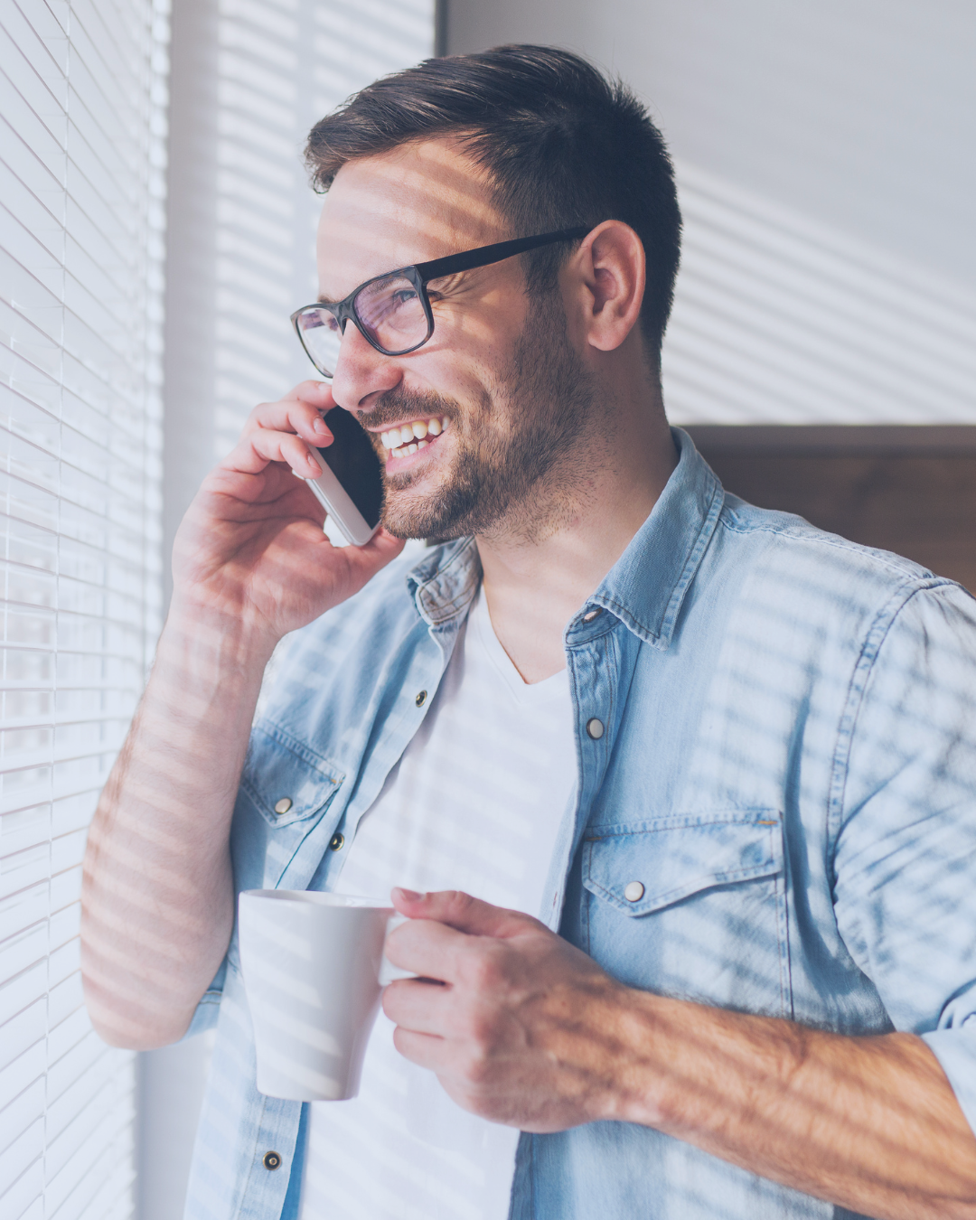 Man talking on a phone and holding a cup in a casual setting