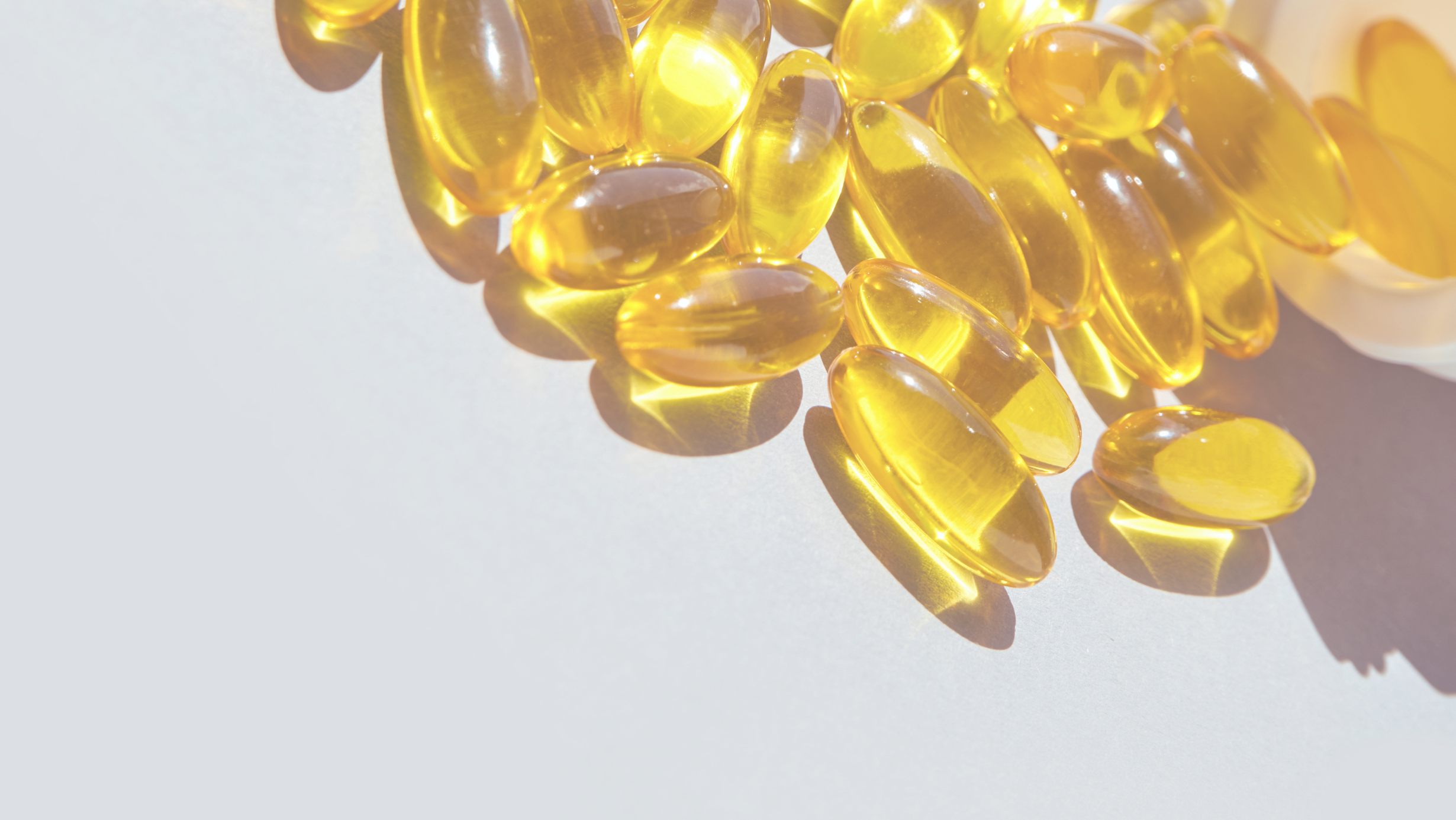 Yellow gel omega 3 capsules on a light grey background